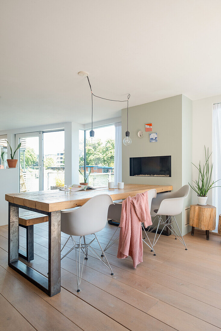 Dining area with wooden table, white chairs and modern hanging lamps