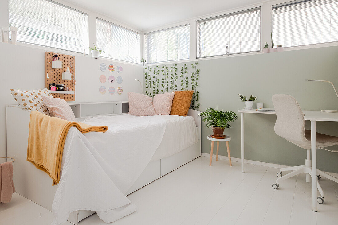 Helles Schlafzimmer mit Einzelbett, Schreibtisch und Pflanzen