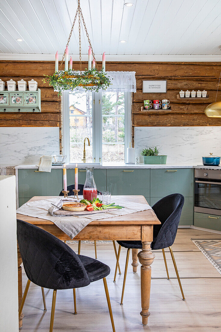 Country kitchen with rustic wooden table and dark velvet chairs