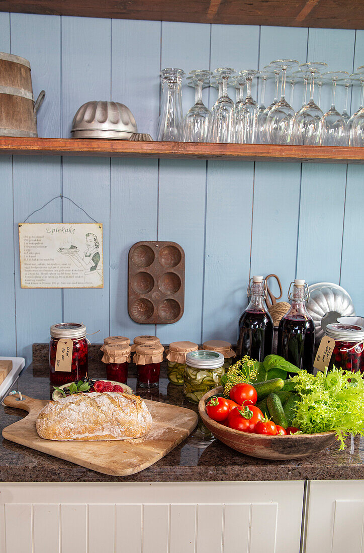 Rustic kitchen counter with fresh bread, preserves and vegetables