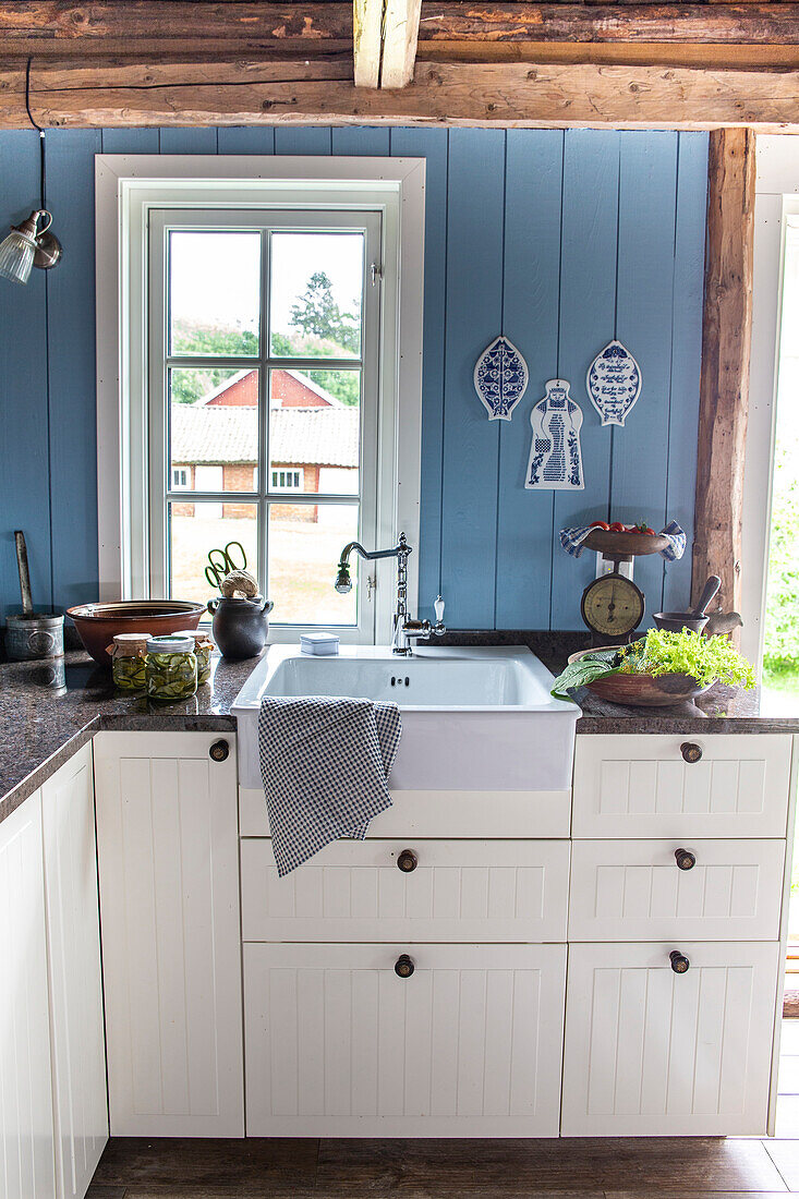 Country-style kitchen with blue wooden panels and rustic wooden beams