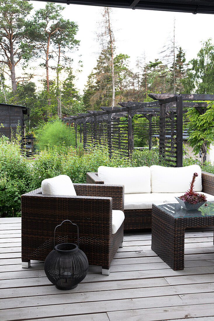 Garten-Sitzecke mit Rattanmöbeln und Laterne auf Holzterrasse