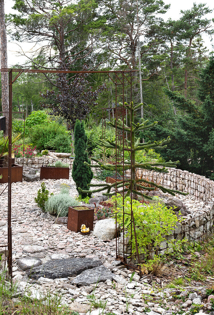 Rock garden with modern metal accents and evergreen plants in summer