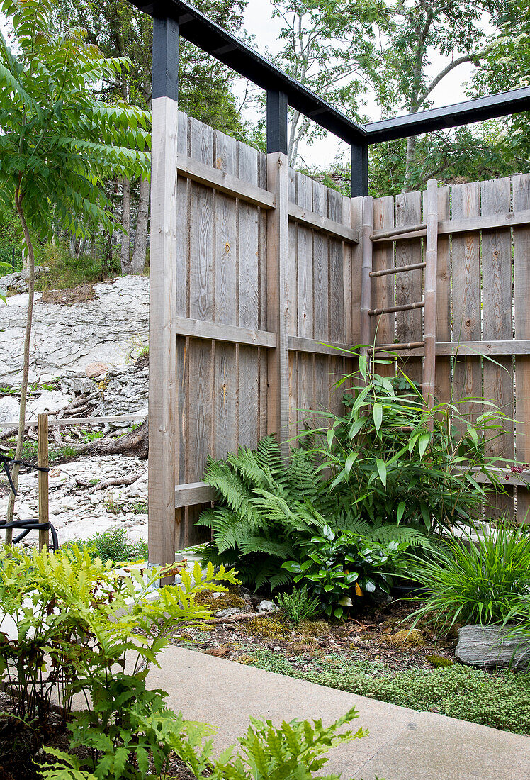 Corner garden area with wooden privacy screen and various green plants