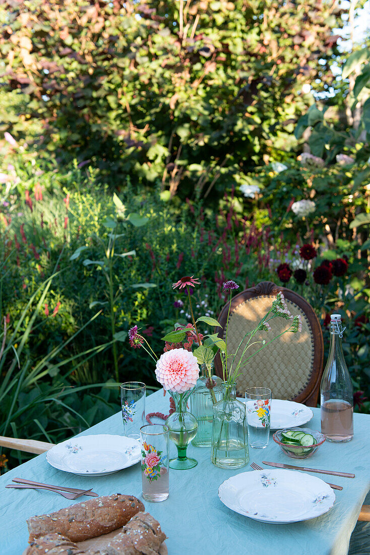 Gedeckter Gartentisch mit Sommerblumen und Brot