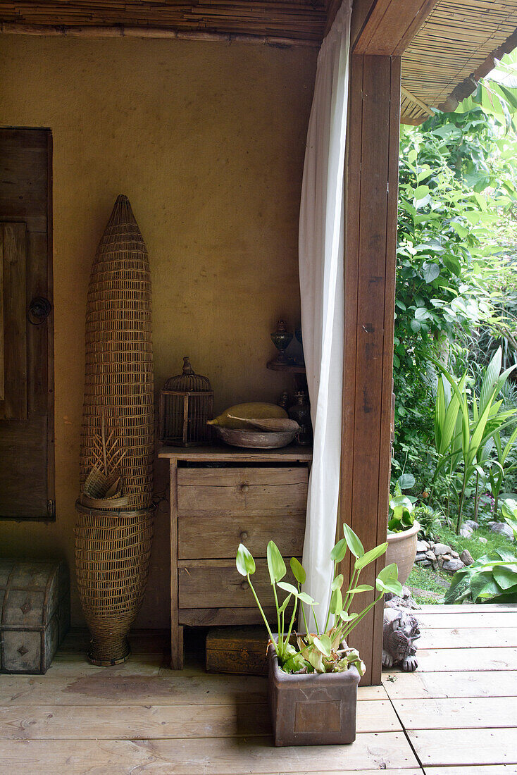 Covered terrace with wooden furniture and potted plant