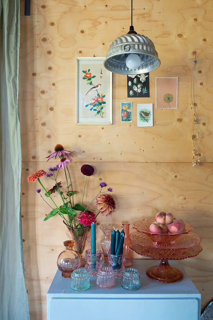 Stilleben mit Blumenarrangement und Obstschale mit Pfirsichen vor Holzwand