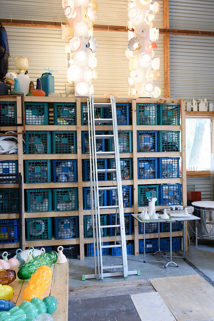 Storage shelf with plastic crates and ladder in workshop