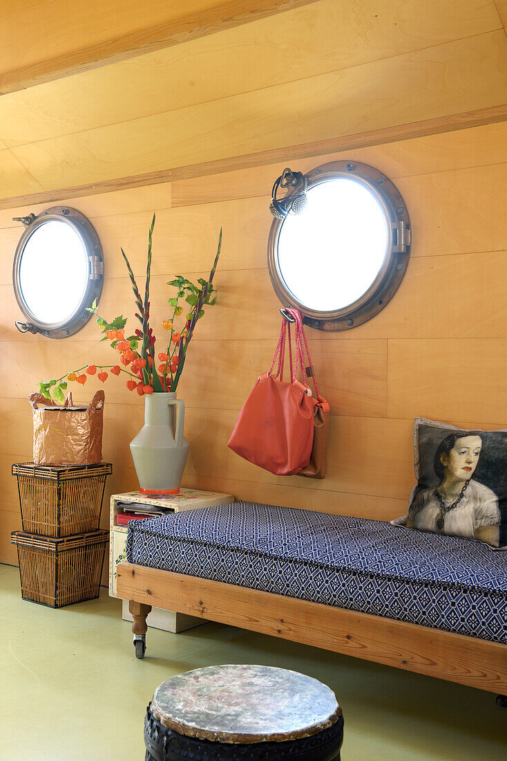 Wood-panelled room with portholes, bench and decorative cushions