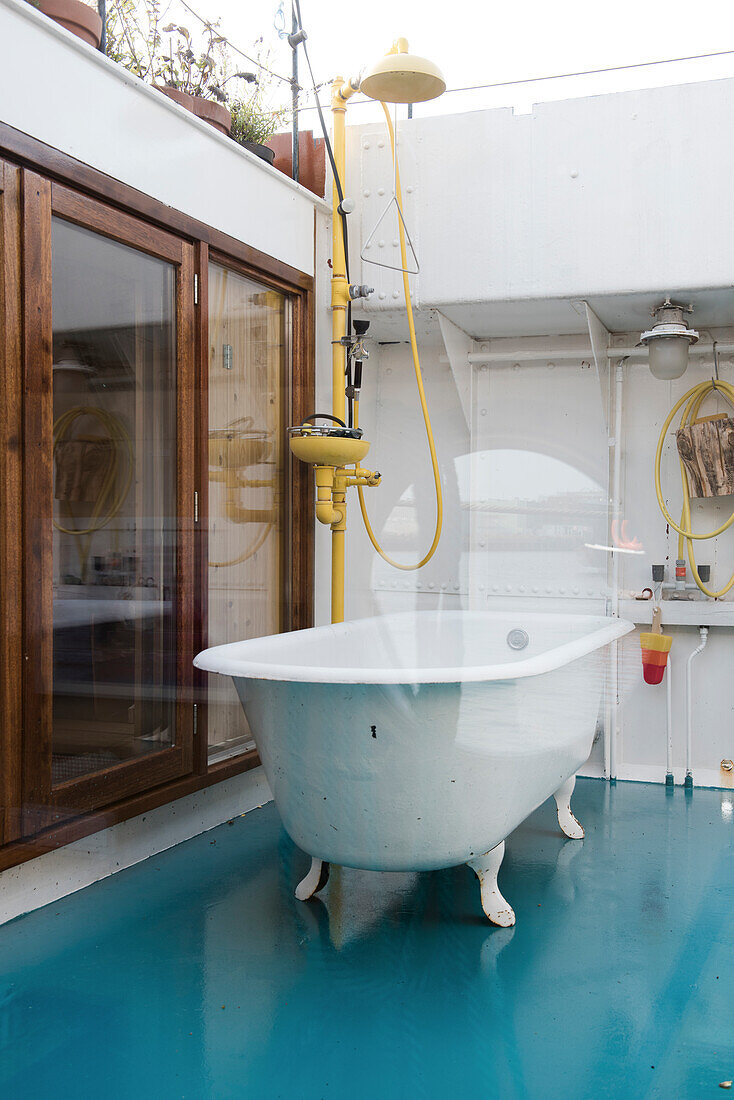 Freistehende Vintage-Badewanne und Außendusche auf blauem Boden