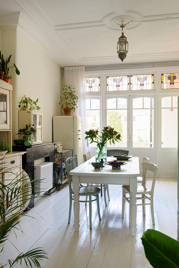 Esszimmer mit weißen Holzmöbeln, Pflanzen und großer Fensterfront