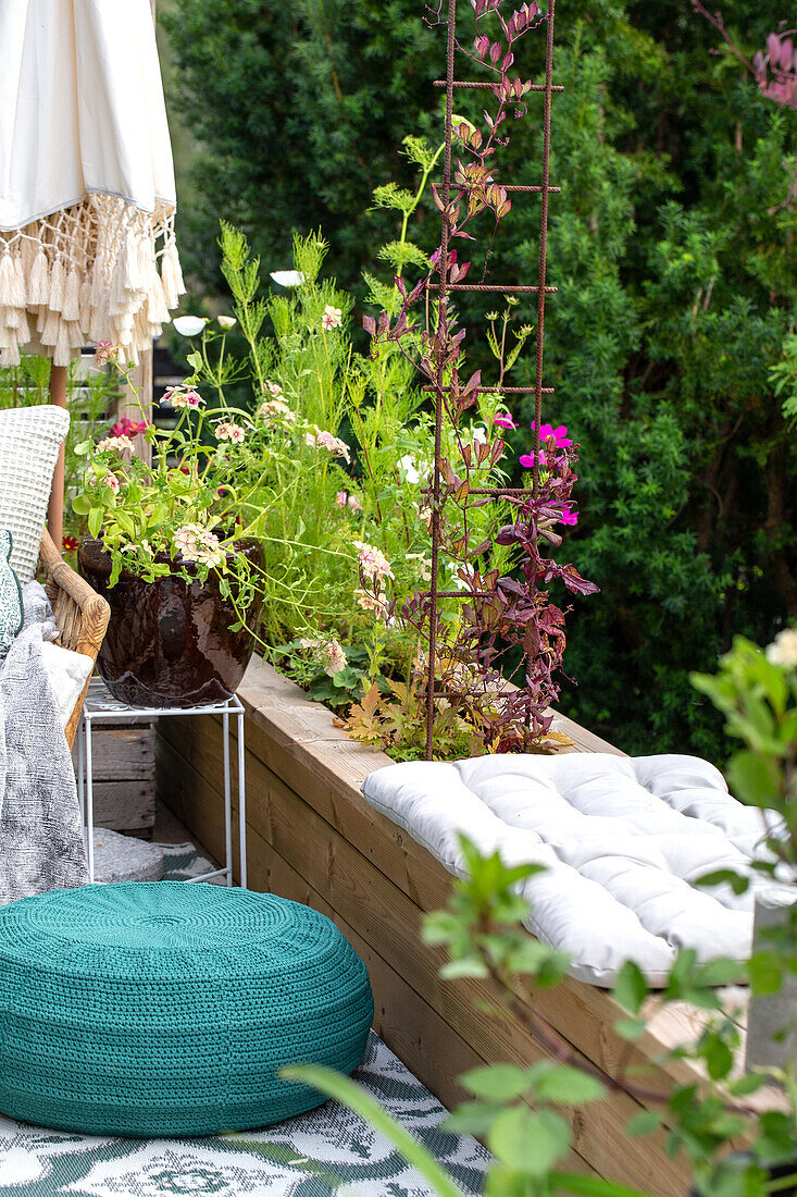 Seating area on terrace with knitted pouf and plants