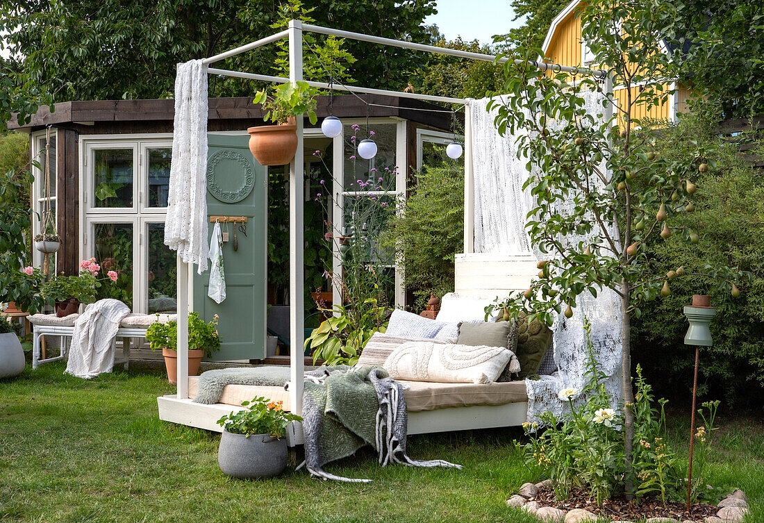 Cosy garden corner with sun bed, cushions and plants in summer