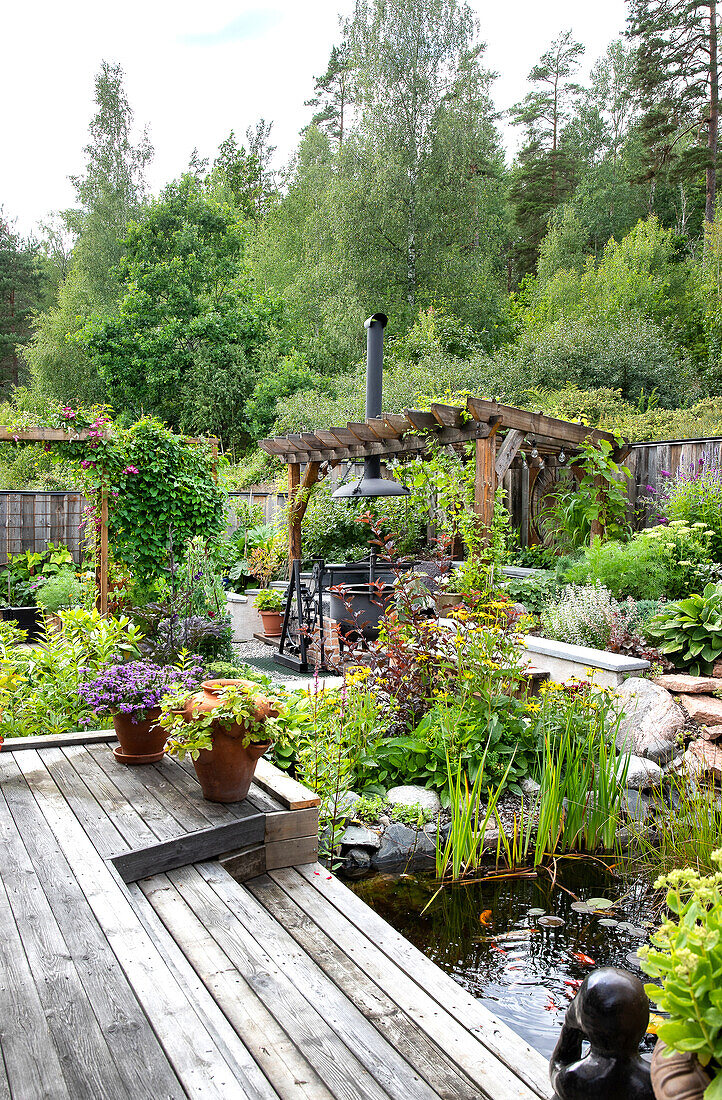 Garden with pond, wooden pergola and lush planting