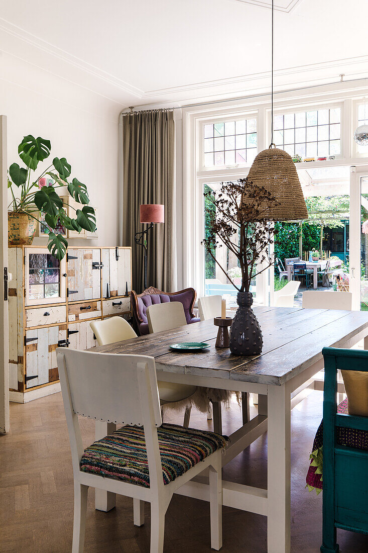 Dining room with wooden table, chairs and bench, view of the garden