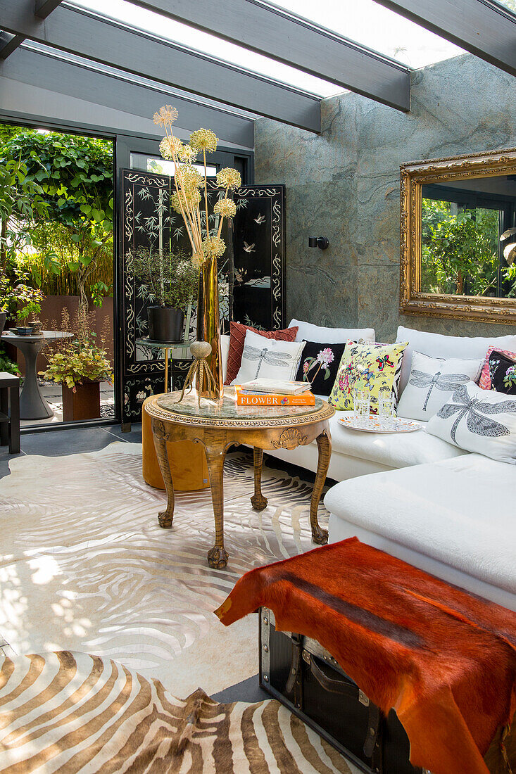 Room with vintage coffee table, plants and patterned cushions on a light-coloured sofa