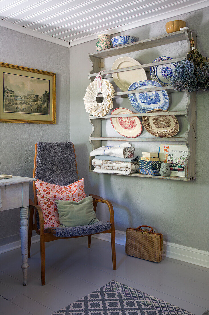 Wooden shelf with crockery and textiles in a vintage corner with chair