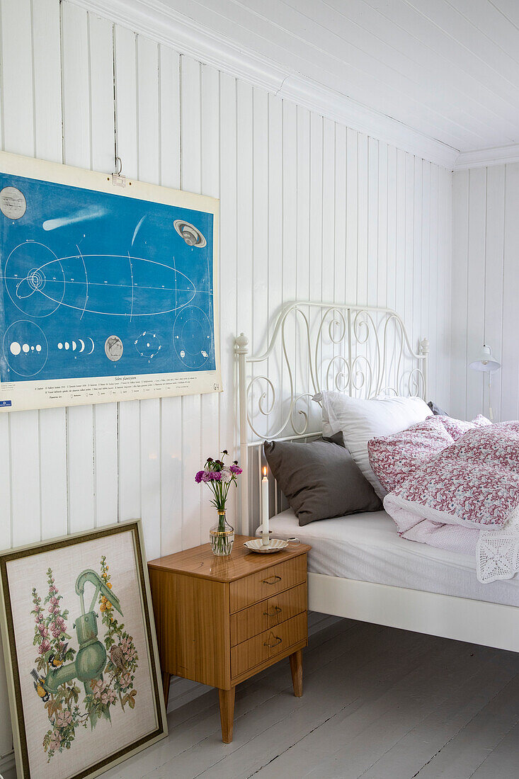 Schlafzimmer mit weißen Holzwänden, Vintage-Bildern und Nachttisch