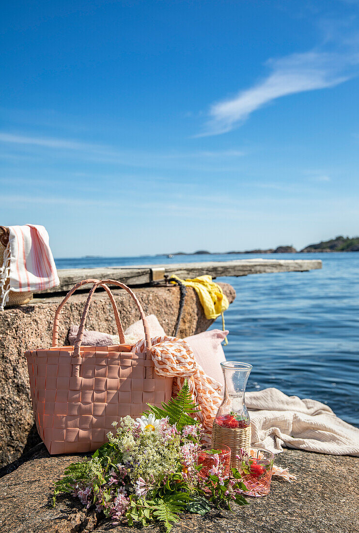 Picnic by the sea with woven bag and wildflowers