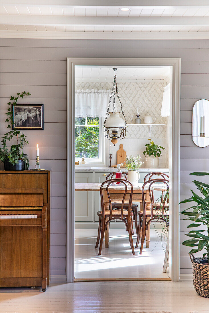 Blick in ein helles Esszimmer mit verspielter Lampe im Landhausstil und Holzstühlen