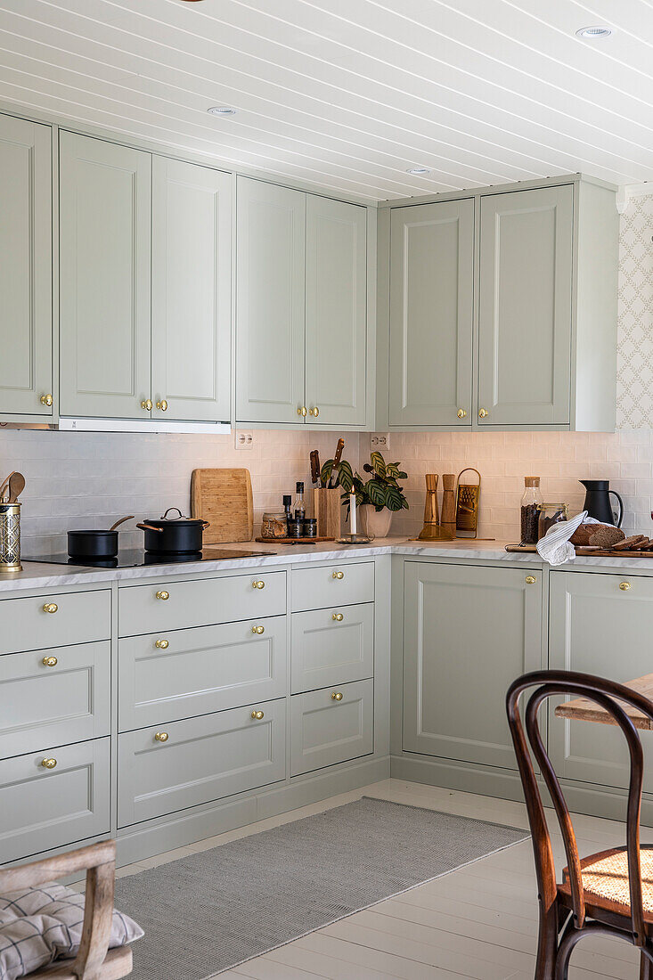 Hellgrüne Küchenschränke mit goldfarbenen Griffen und weißer Decke