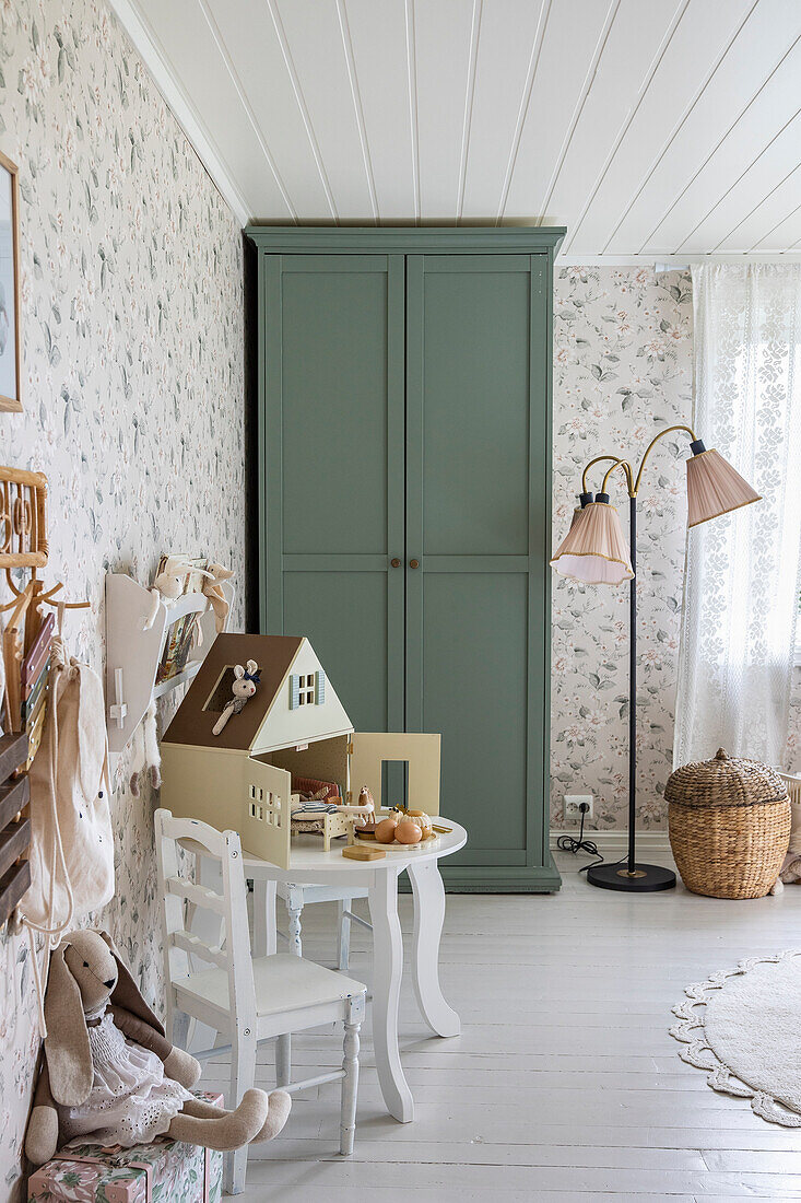 Children's room in pastel colours with green cupboard, toys and floral wallpaper