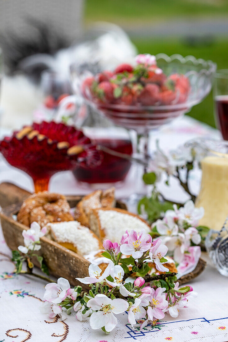 Gartenpicknick mit Apfelblüten (Malus domestica), Gebäck und Getränken