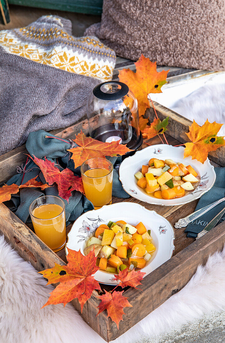 Herbstliches Frühstück im Freien mit Obstsalat und Ahornblättern