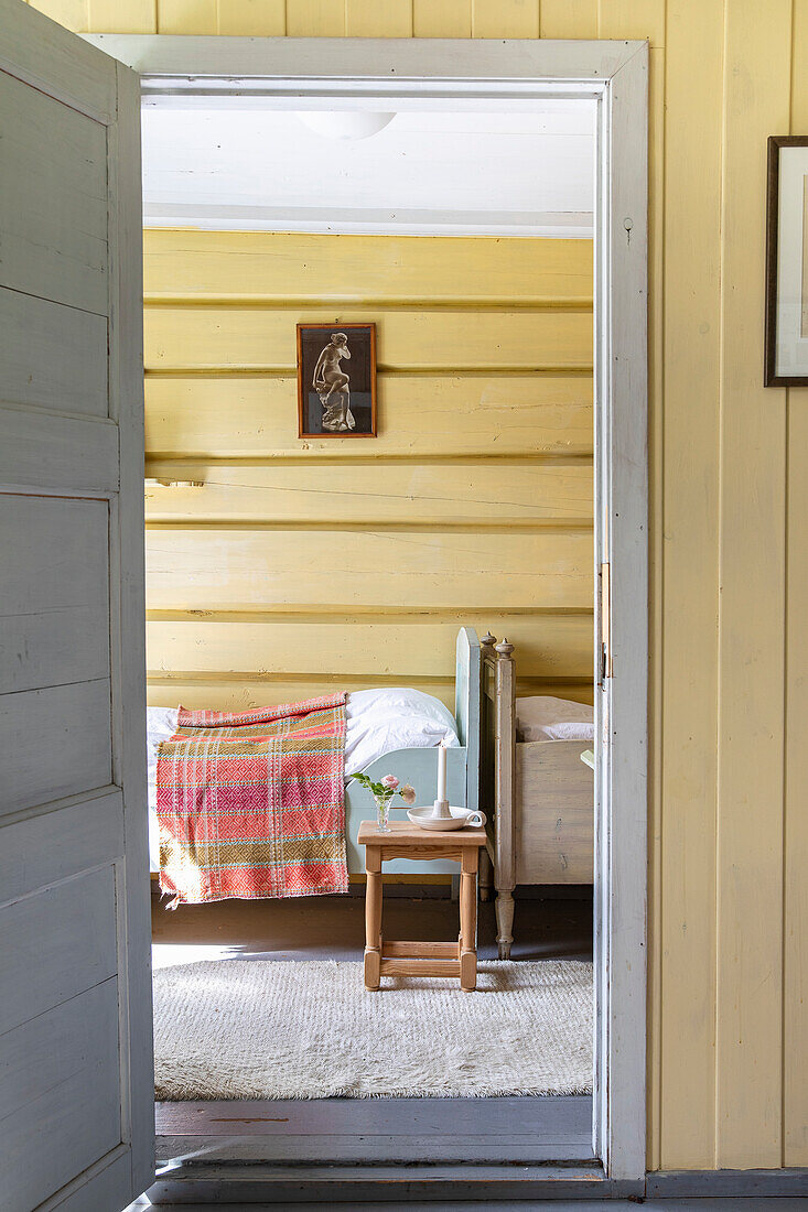 Blick durch offene Tür in ein rustikales Schlafzimmer mit gelben Wänden