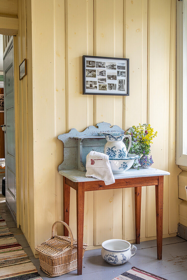 Holztisch mit Waschschüssel, Krug und Blumenstrauß im Landhausstil