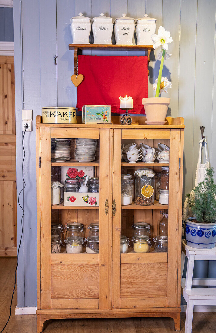 Wooden display cabinet with crockery, preserving jars and decorative elements