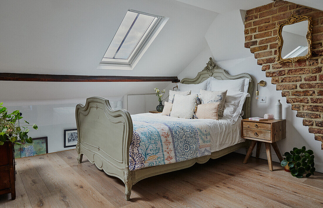 Dachgeschoss-Schlafzimmer mit antikem Bett, Ziegelwand und Dachfenstern