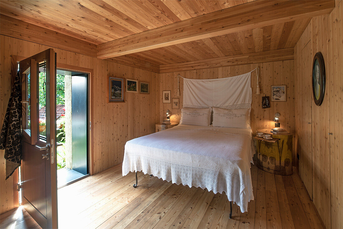 Bedroom with wood-paneled walls and a double bed with lace bed linen