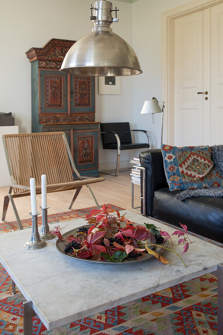 Couchtisch mit Herbstdekoration in Wohnzimmer mit Ledersofa und Bauernschrank