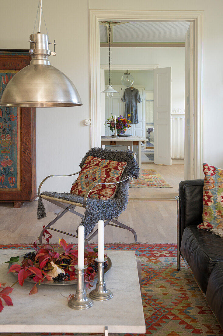 Metal hanging lamp above living room table, patterned rug and leather sofa