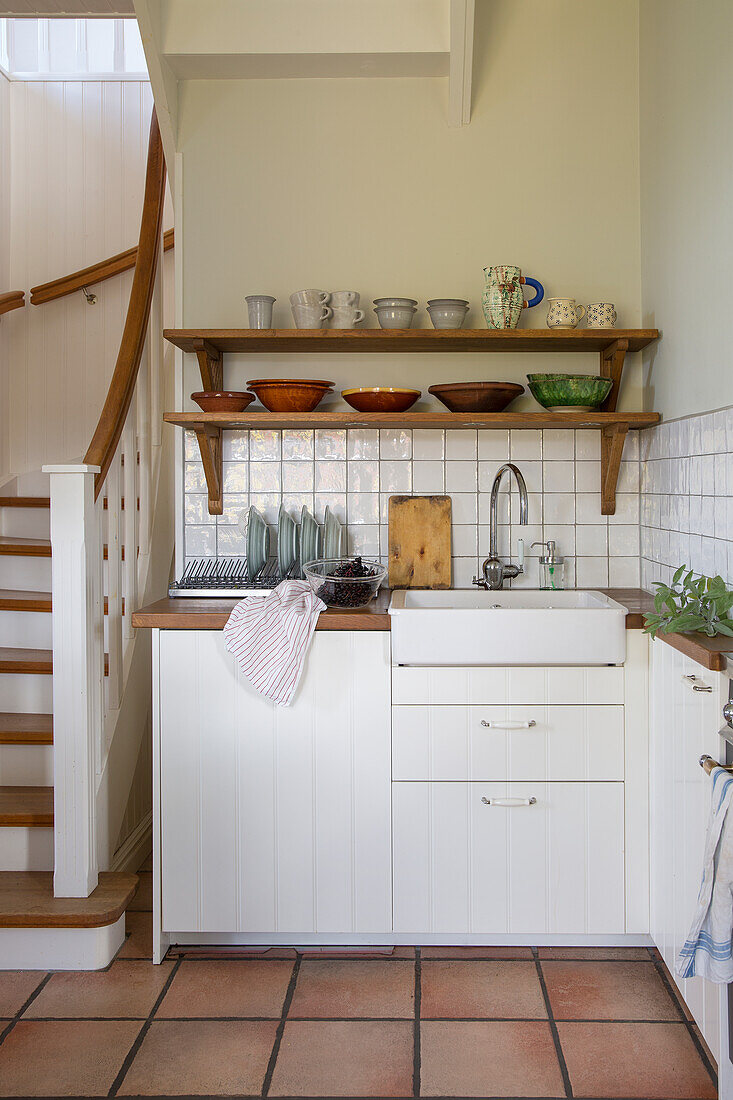 Kleine Landhausküche mit Holzregalen und Terrakottafliesen