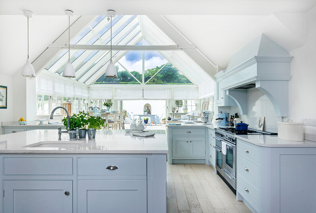 Modern kitchen with light blue cupboards and conservatory extension in the background