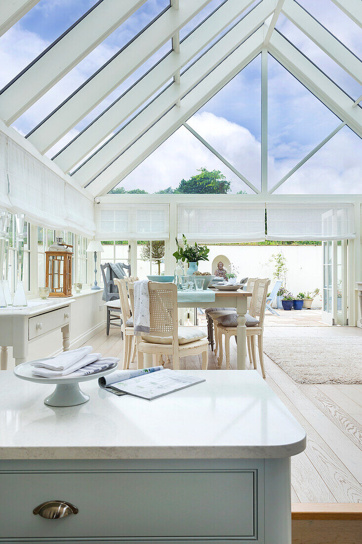 Bright conservatory with dining table and white furniture