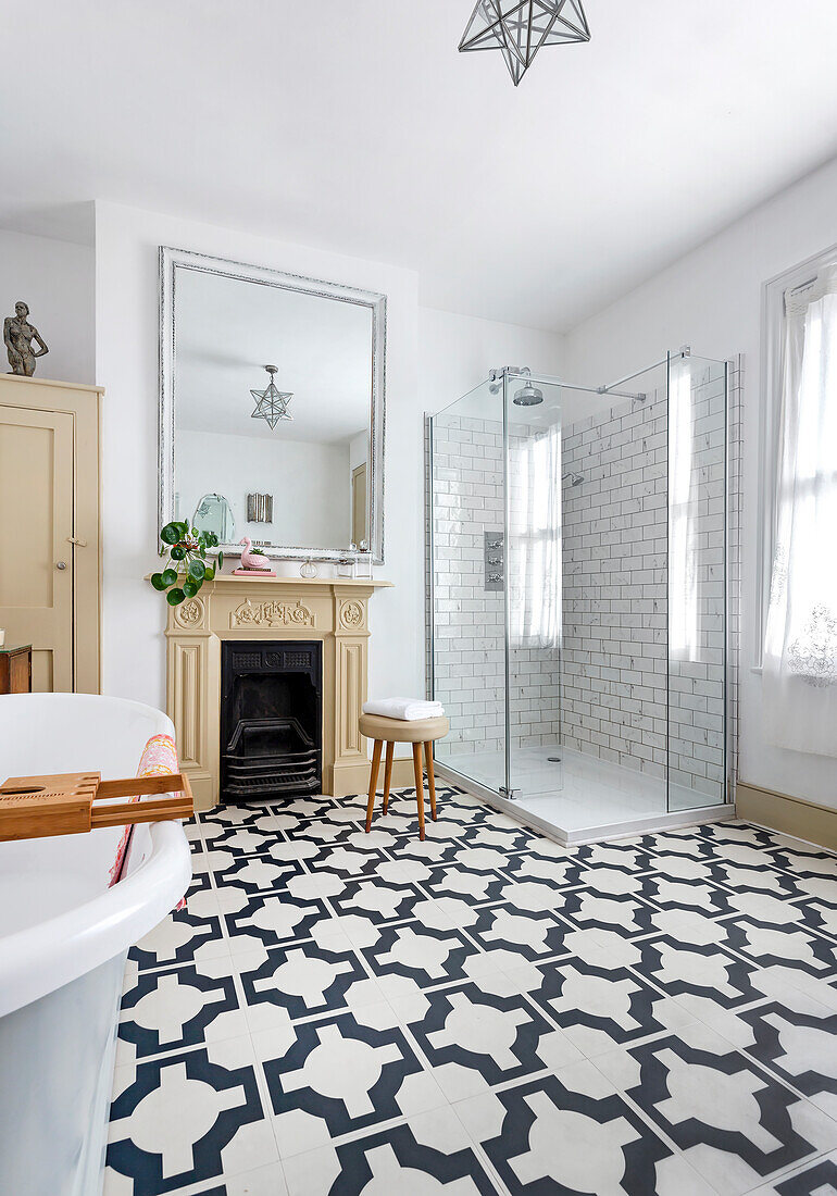 Bright bathroom with geometrically patterned floor tiles and glass shower stall