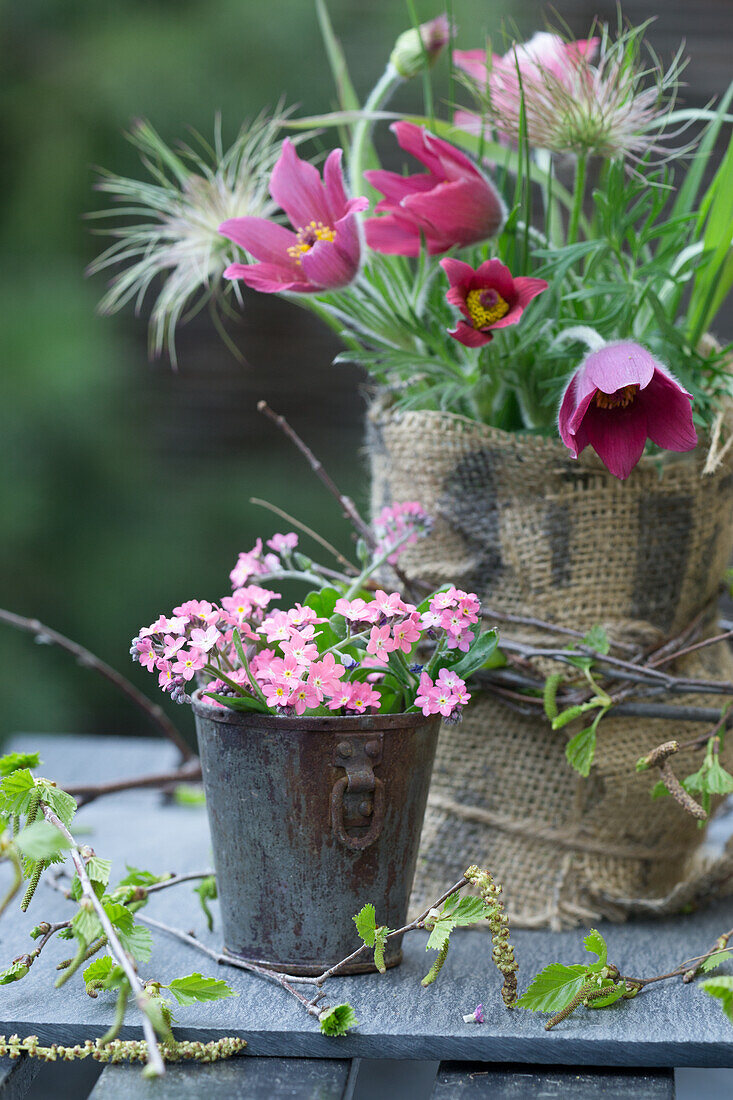DIY vase made of jar and sacking with pasque flower, pink forget-me-not in vintage bucket