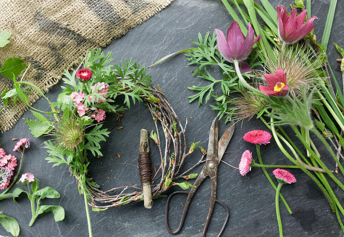 Wreath made of pasque flower (Pulsatilla), forget-me-not, daisies (Bellis) and birch twigs