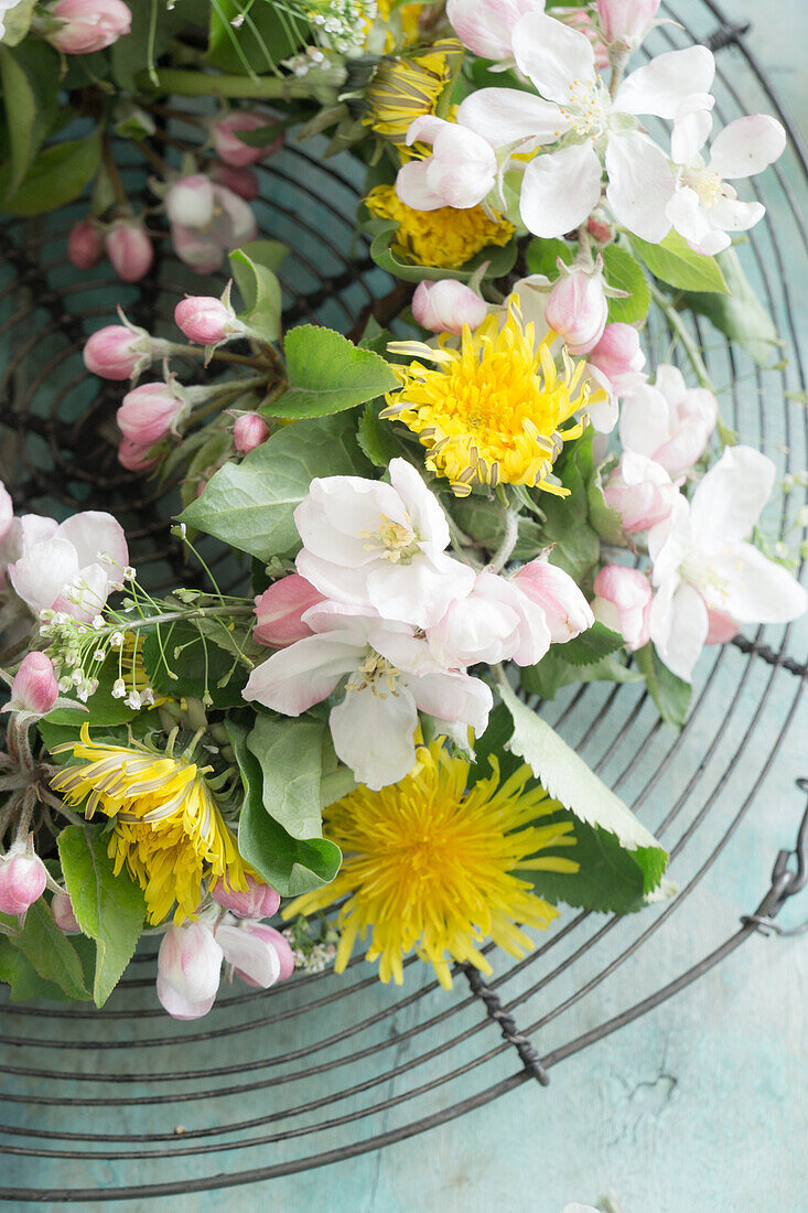 Wreath of apple blossoms and dandelions on a cake rack