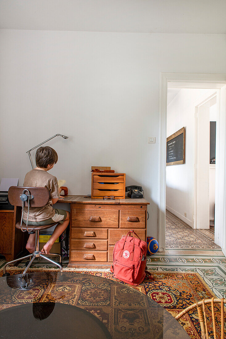 Junge sitzt am Schreibtisch im Kinderzimmer