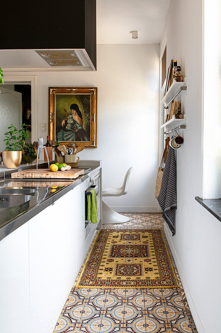 Long, narrow kitchen with patterned tiles and painting on the wall