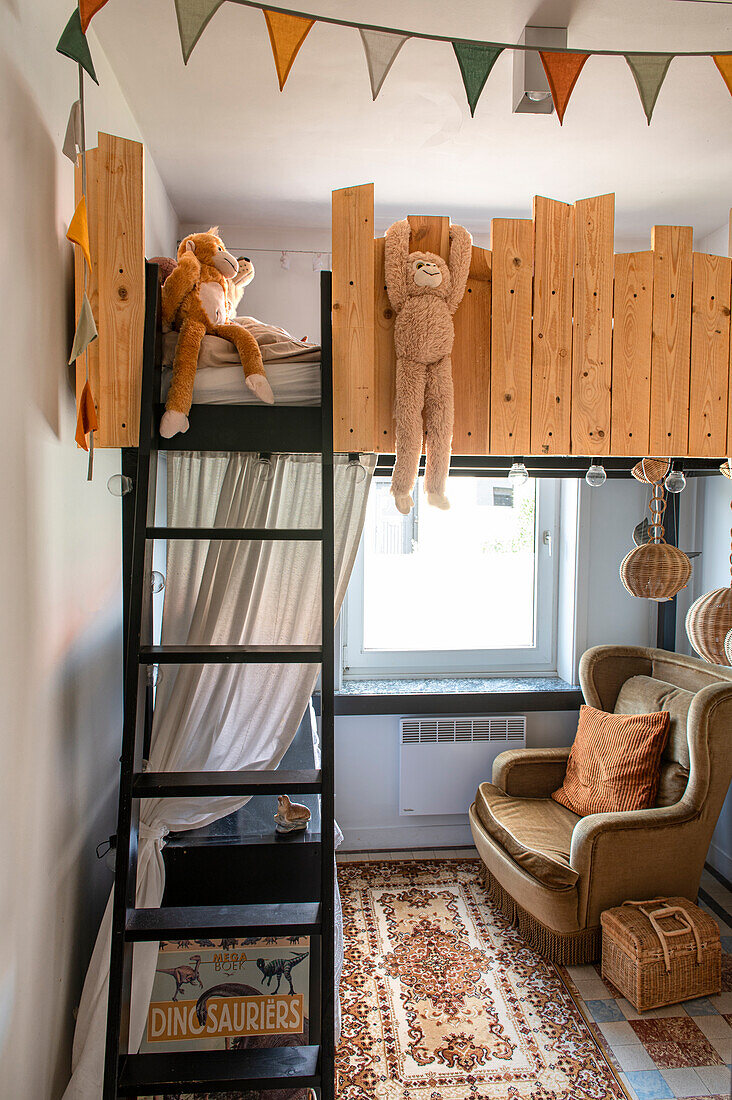 Kinderzimmer mit Hochbett aus Holz, Lesesessel und Teppich mit orientalischem Muster