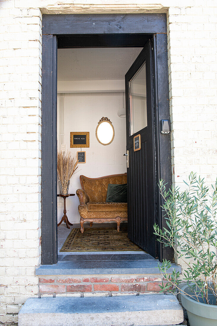 Open front door to an entrance area with antique sofa and mirror