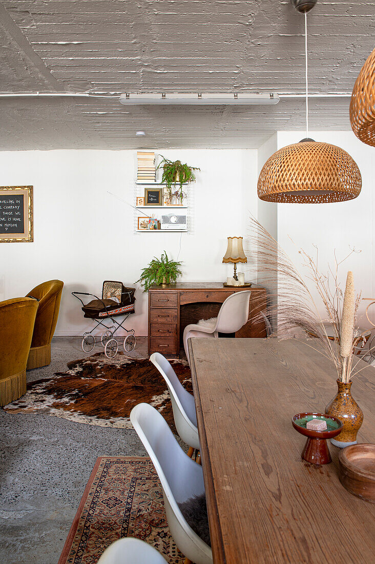 Dining area with wooden table, rattan lamps and retro decor in the adjoining living room