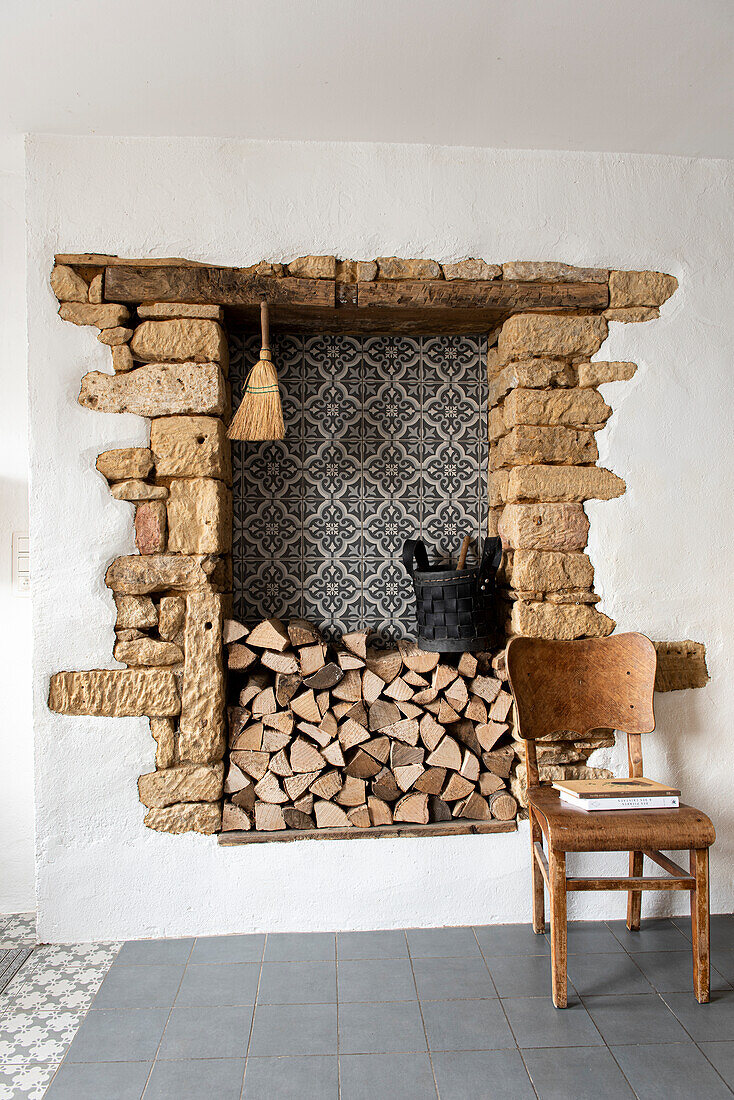 Walled-in fireplace with wood pile and vintage chair in rustic design