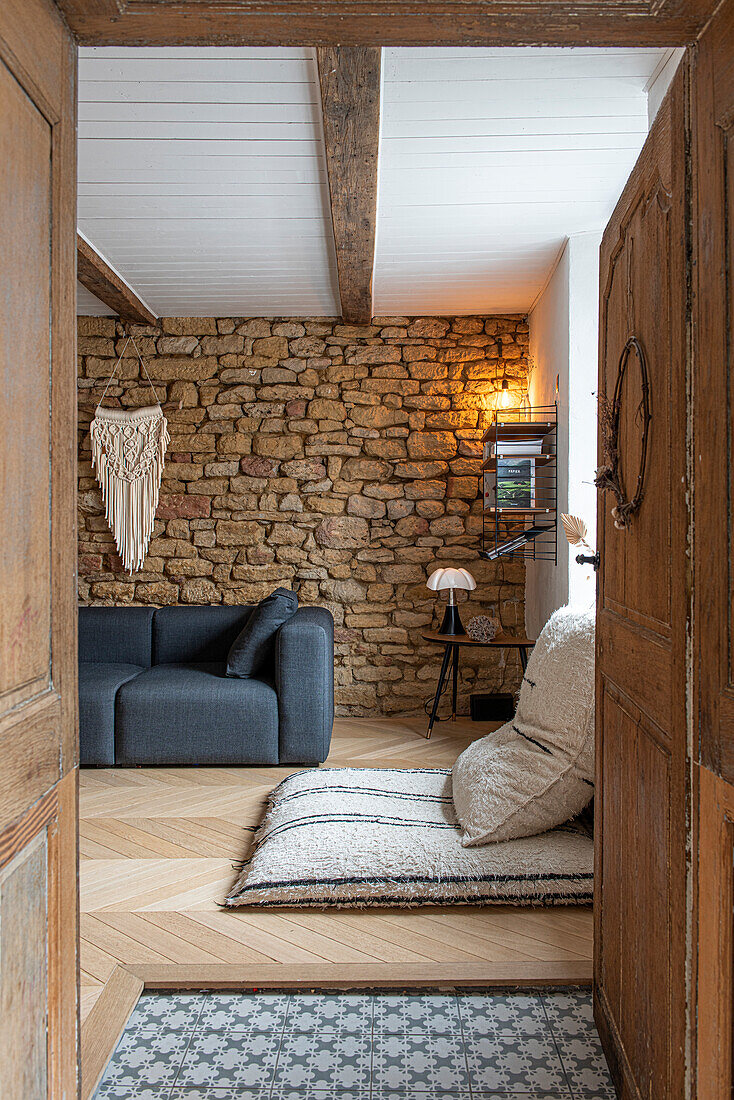 Rustikales Wohnzimmer mit Natursteinwand und Holzbalkendecke