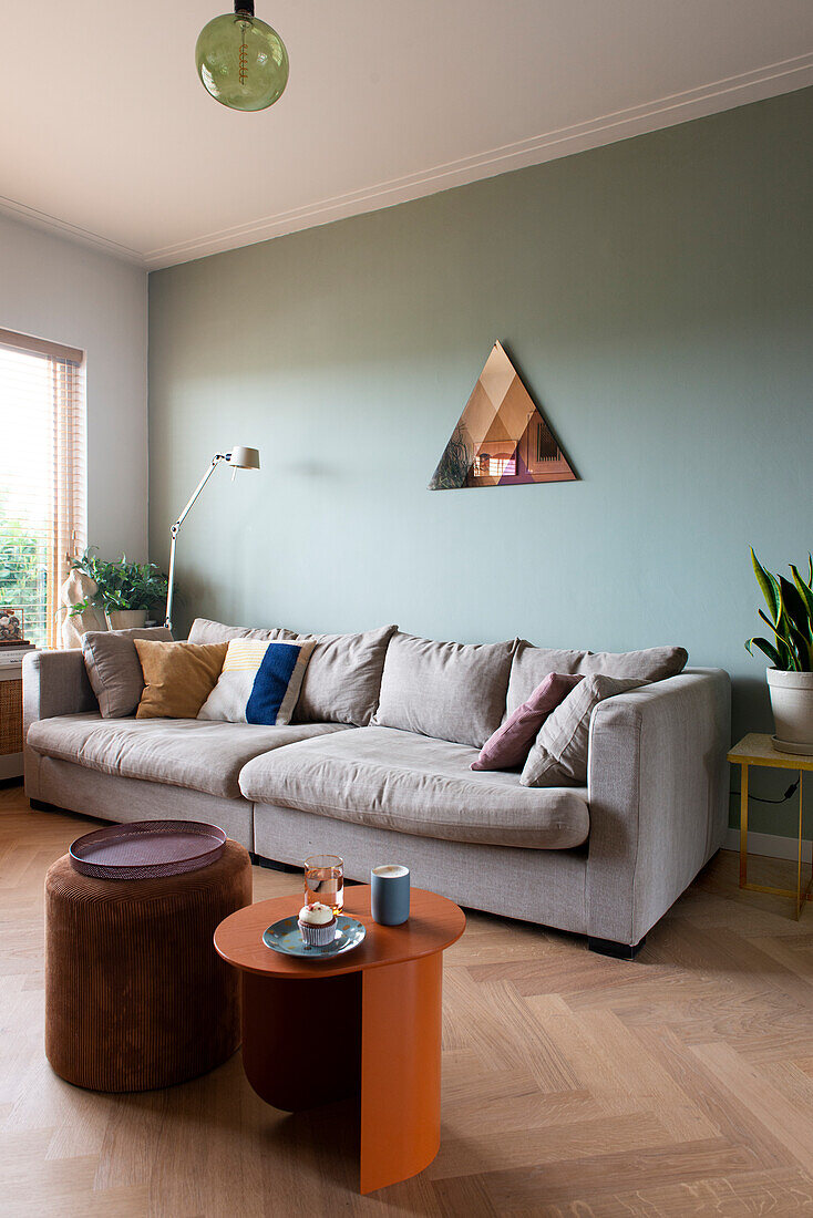 Spacious living room with light grey sofa and geometric decorative mirror on the wall